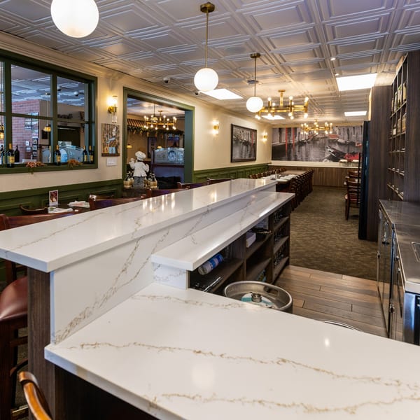 The interior of Di Leone's Italian Restaurant, featuring a long white marble bar and dining area.