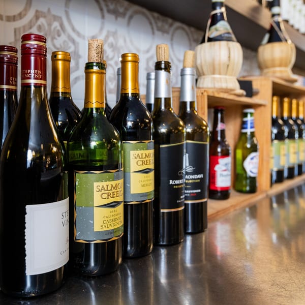 A close-up of various wine bottles and beer bottles displayed on a counter at Di Leone's Italian Restaurant.