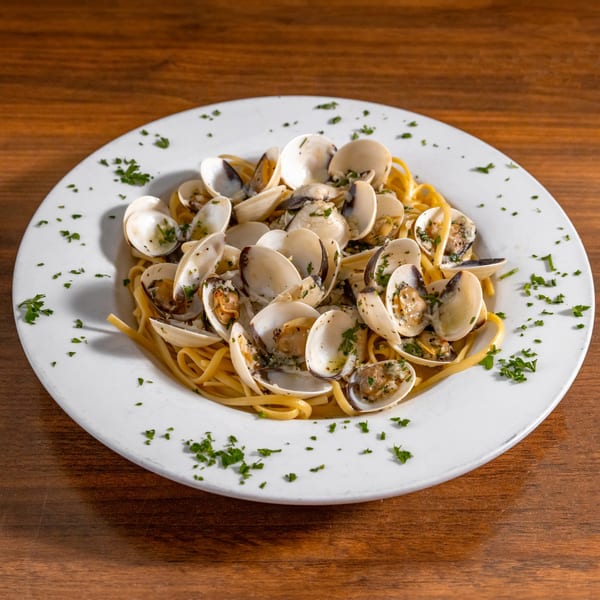 Di Leone's linguine with clams, garnished with fresh parsley, on a white plate.