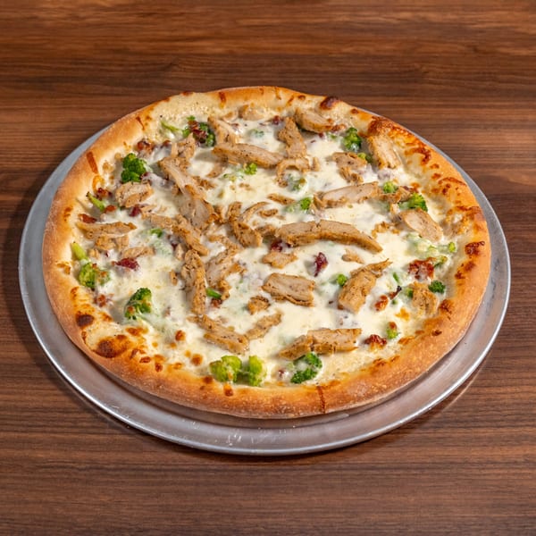 Di Leone's Italian Restaurant's chicken and broccoli pizza on a metal pan, on a wooden table.
