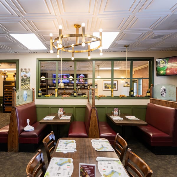 Interior of Di Leone's Italian Restaurant with red booths, wooden tables, and a window displaying wine bottles.