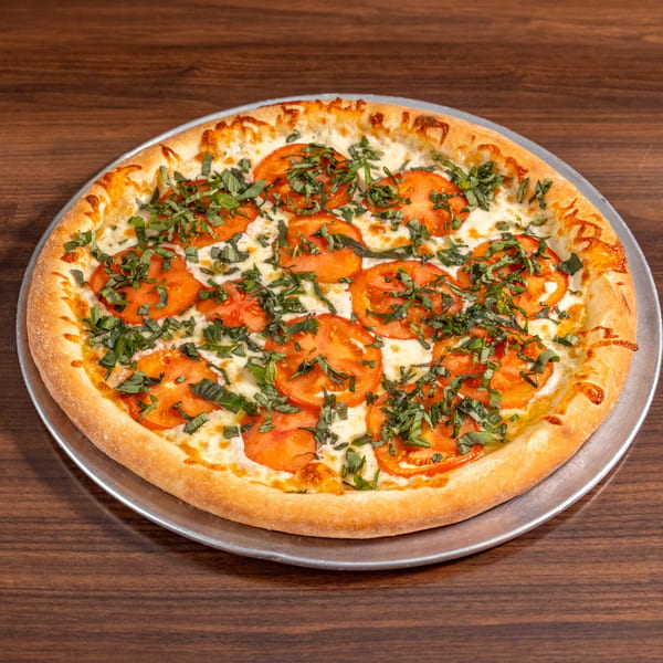 A freshly baked Di Leone's Italian pizza with sliced tomatoes, melted cheese, and basil on a metal pan.