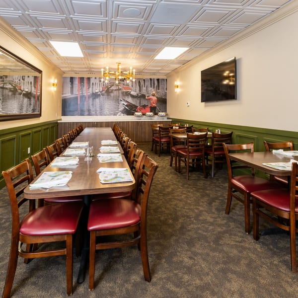 Di Leone's Italian Restaurant dining room with long tables, red chairs, and a Venice mural.