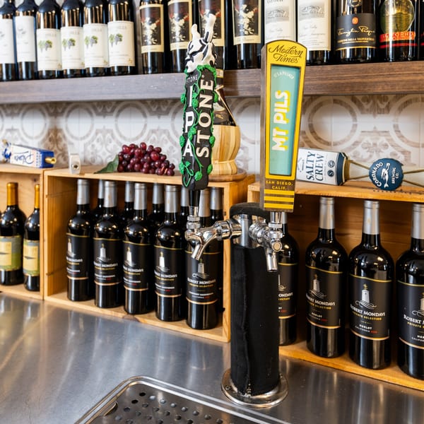 Beer taps and wine bottles on shelves, with a bunch of grapes, at Di Leone's Italian Restaurant.