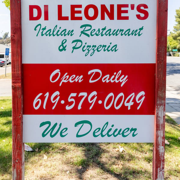Di Leone's Italian Restaurant & Pizzeria sign, red and white with green text, advertising delivery.