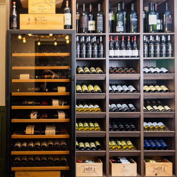 A large, well-stocked wine cellar with a variety of red and white wines in bottles and wooden crates.