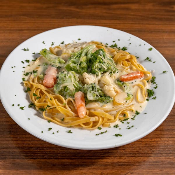 Di Leone's Italian Restaurant's creamy fettuccine pasta with broccoli, carrots, and cauliflower on a white plate.