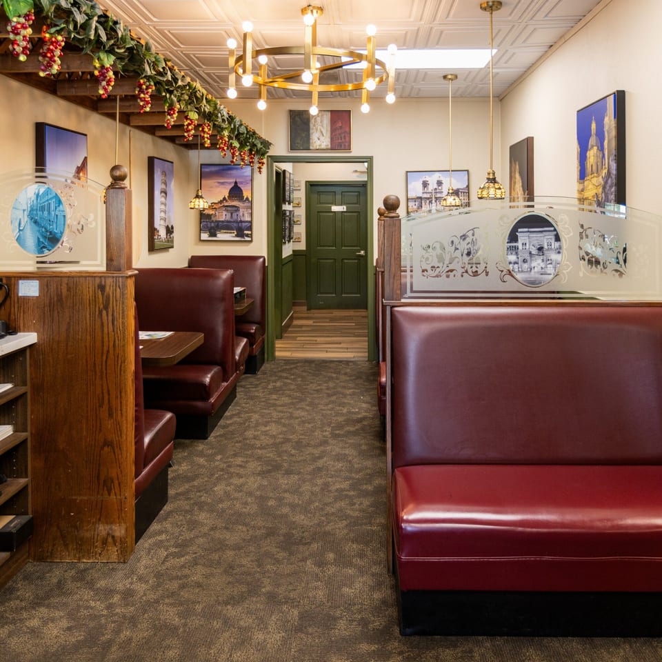 Interior of Di Leone's Italian Restaurant with red booths, Italian artwork, and grapevines adorning the ceiling.