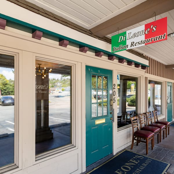 Exterior of Di Leone's Italian Restaurant with a green door, large windows, and a hanging sign.