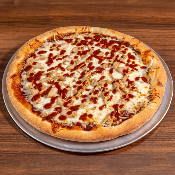 A whole BBQ chicken pizza with melted cheese and sauce on a metal pan.