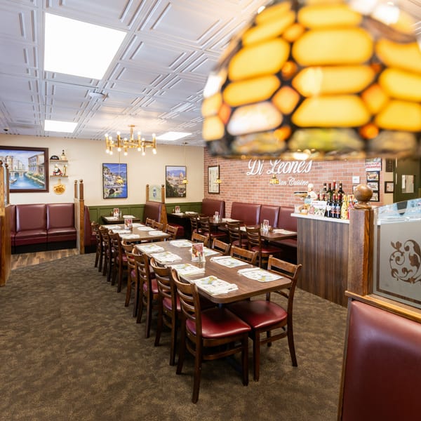 Interior of Di Leone's Italian Restaurant with dining tables, red booths, and Italian-themed decor.