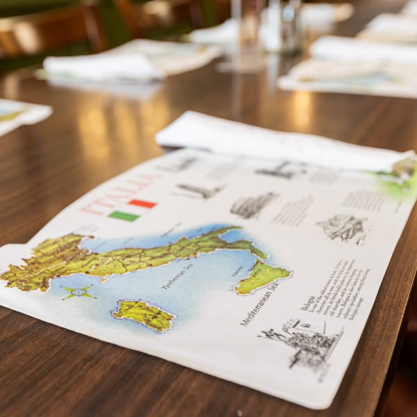A placemat with a map of Italy and information about Bologna on a wooden table at Di Leone's.