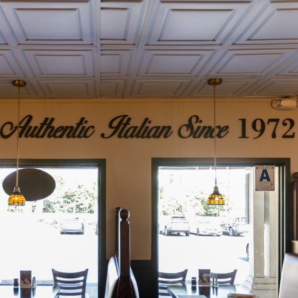 Di Leone's Italian Restaurant interior with "Authentic Italian Since 1972" sign, tables, and windows.