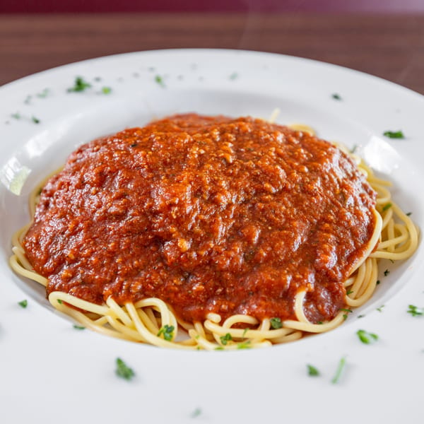 Di Leone's spaghetti with rich red meat sauce and parsley on a white plate.